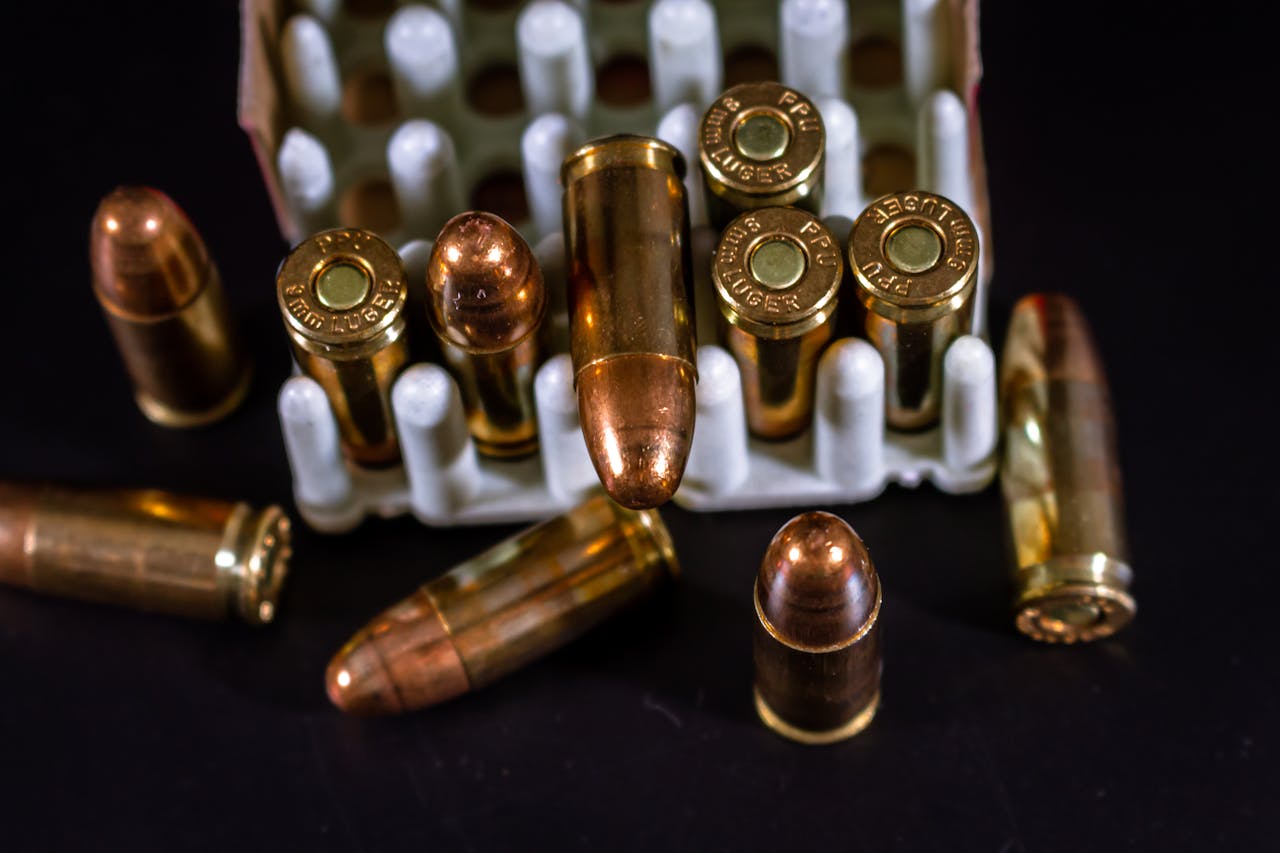 Detailed view of copper bullets and cartridge cases in a container against a dark background.